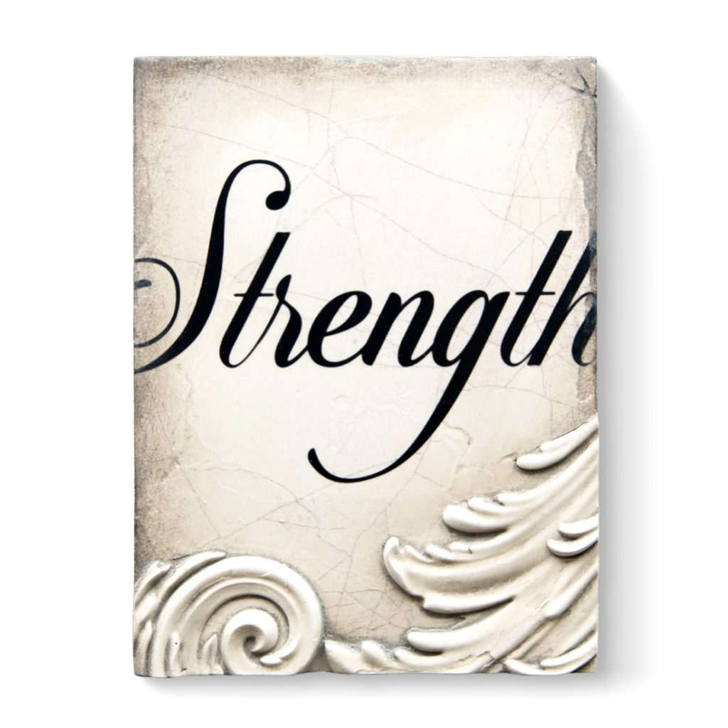 A white sculptural block decorated with 3D filigree along the bottom and the word "Strength" written in cursive, through the middle of the block, on it.