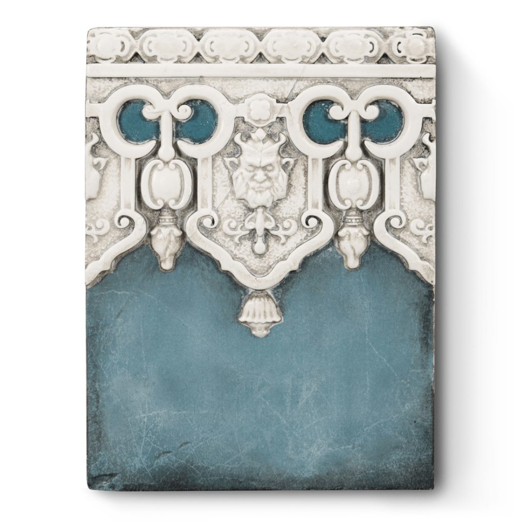 A sculptural block decorated with details of white architectural molding on a blue background. The molding is decorated with gargoyles meant to be lions faces.