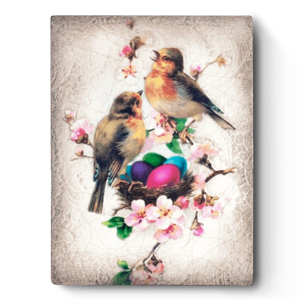 A white sculptural block with a vintage photo of birds at their nest full of brightly colored eggs, a faint vintage wallpaper is carved into the block.